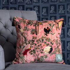 a pink pillow sitting on top of a gray chair next to a wallpapered wall