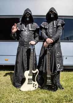 two people dressed in black are holding guitars