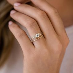 a woman's hand wearing a gold ring with two diamonds on it and one diamond in the middle