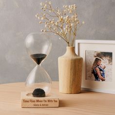 an hour - glass sand timer sits on a table next to a vase with flowers