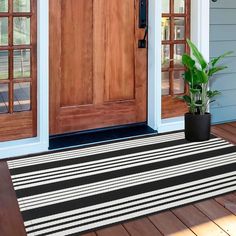 a black and white door mat sitting on top of a wooden floor next to a potted plant