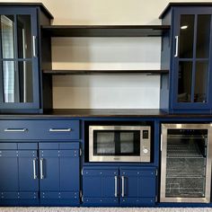 an empty kitchen with blue cabinets and stainless steel oven, microwave and dishwasher