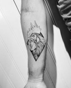 a black and white photo of a rooster tattoo on the left arm, with a heart in the middle