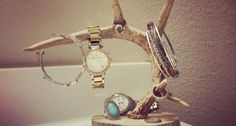 a wooden stand with watches and bracelets sitting on top of a white bathroom sink