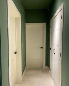 an empty hallway with two white doors and green walls