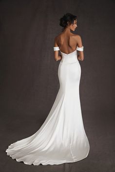 the back of a woman in a white wedding dress with her hands on her hips