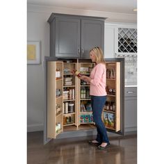 a woman is opening the door to an open refrigerator in a kitchen with gray cabinets