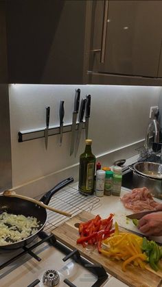 a person cooking food in a pan on the stove top next to a cutting board