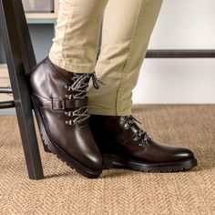 a person wearing brown boots and tan pants standing on top of a chair with their legs crossed