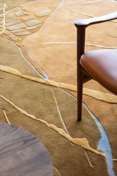 a brown chair sitting on top of a wooden floor next to a rug covered in leaves