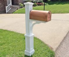 a mailbox on the side of a road in front of a house with grass