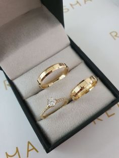 two gold rings sitting in a box on top of a table