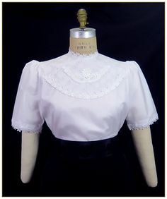 "Poly/Cotton Ultima Broadcloth. Color: White. Comfortable soft poly/cotton blend broadcloth fabric with floral white lace front yoke and large white rose applique. Rose leaf white trim around neckline, on hem of sleeves and front bodice. Lightly gathered short sleeve and button back closure. Generously cut for comfort. Machine washable. Circa 1900-1910. Made in U.S.A. Sizes: SM, MED, LG & XLG. Blouses ordered by bust measurement, inches:  BUST           SIZES 32\" - 34\"     SMALL 35\" - 39\"     MEDIUM 40\" - 44\"     LARGE 45\" - 49\"     XLARGE Blouses ordered by bust measurement, centimeters: SMALL       81 cm - 86 cm MEDIUM    88.9 cm - 99 cm LARGE      101.6 cm - 111.76 cm XLARGE    114 cm - 124.46 cm HOW TO MEASURE TO DETERMINE YOUR SIZE: BUST: Measure the fullest part of your bust, Feminine Fitted Cotton Lace Top, White Lace Patchwork Cotton Top, White Cotton Lace Patchwork Top, Feminine Cotton Tops With Lace Sleeves, White Cotton Lace Top With Patchwork, Fitted Lace Top With Crochet Trim, Elegant Fitted Lace Top With Crochet Trim, White Short Sleeve Tops With Lace Details, White Short Sleeve Top With Lace Sleeves