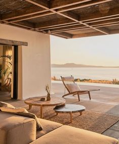 a living room with couches and tables on the floor next to an ocean view