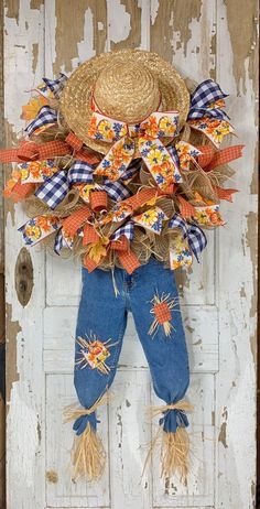 a scarecrow door hanger with a straw hat and sunflowers on it