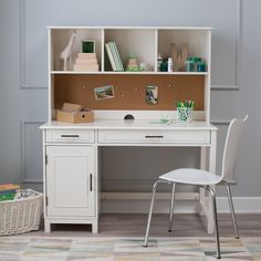 a white desk and chair in front of a gray wall with a corkboard on it