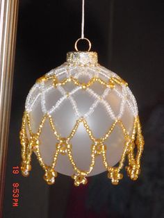 a glass ornament hanging from a pole in front of a window with beads on it