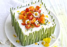 a white plate topped with a cake covered in fruit and veggies