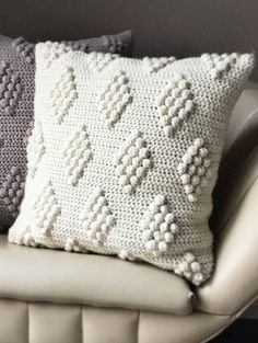 three pillows sitting on top of a white couch