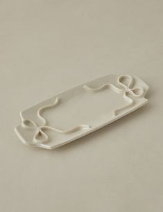 a white tray with an abstract design on the bottom and handles, sitting on a gray surface