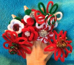 a hand is holding several red and white flowers on a blue blanket with glittery bows