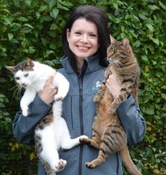 a woman holding three cats in her arms