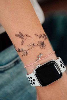 a woman's arm with a bird and flower tattoo on it, which is attached to an apple watch