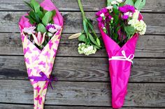 two pink umbrellas with flowers tied to them sitting on a wooden table next to each other