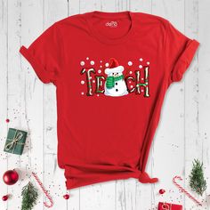 a red t - shirt with a snowman wearing a santa hat and the word happy on it