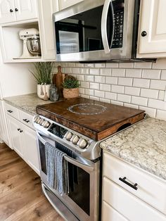 a kitchen with white cabinets and stainless steel appliances, including an electric range hood over the stove