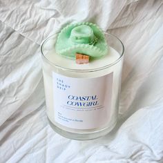 a candle that is sitting on top of a white sheet with the label coastal cowgirl