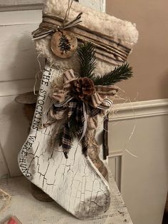 a christmas stocking hanging from the side of a door with pine cones and ribbon