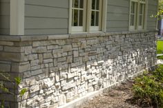 a house with a stone wall and white windows