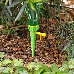 a green and yellow toy umbrella sitting in the middle of some leaves on the ground