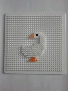 a white lego board with orange and black beads on the bottom, and a smiley face in the middle