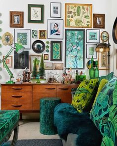 a living room filled with furniture and lots of pictures on the wall next to a plant