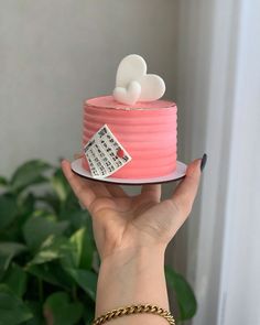 a woman holding a pink cake with white hearts on top