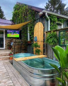 an outdoor hot tub in front of a building with a screen on the outside wall