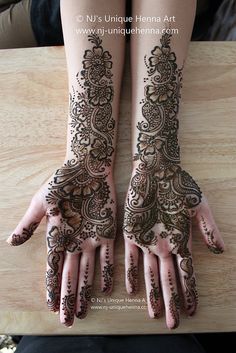 two hands with henna tattoos on them, one is showing off the intricate design