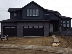 a large house with two car garages on the front and side of it, surrounded by dirt