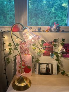 a desk with a lamp and pictures on the wall next to it in front of a window