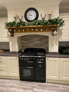 a kitchen with an oven, stove and clock on the wall above it's mantle