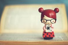 a small figurine with glasses and a red hair is standing on an open book