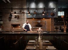 a man standing in front of a kitchen counter next to a table with plates and glasses on it