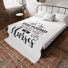 a bed with a white comforter and pillows on it in a room next to a brick wall