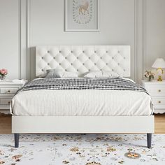 a white bed sitting in a bedroom on top of a wooden floor next to a dresser