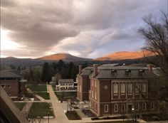 an aerial view of a campus with mountains in the background and cloudy skies above it