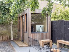 a small wooden building sitting in the middle of a yard next to a table and chairs