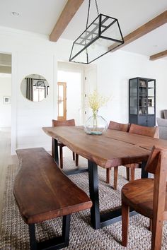 a dining room table with benches and a vase on the centerpiece in front of it