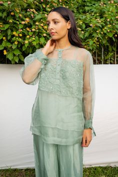 Green silk organza 3D hand embroidered shirt with floral motifs. Comes with an inner.
Components:2
Pattern:Embroidered
Type of Work:Hand Embroidered
Neckline:Round
Sleeve Type:Puffed sleeves
Fabric:Shirt: 100% Silk Organza, Inner: Viscose Tabby
Color:Green
Other Details:
Note: The pant worn by model is not for sale.
Occasion:Party,Work - Aza Fashions Elegant Chanderi Tops With Intricate Embroidery, Elegant Tops With Intricate Embroidery In Chanderi, Silk Long Sleeve Blouse With Sheer Dupatta, Festive Elegant Blouse With Sheer Sleeves, Elegant Blouse With Resham Embroidery In Organza, Organza Blouse With Chikankari Embroidery For Party, Elegant Tissue Silk Blouse With Floral Embroidery, Elegant Organza Blouse With Resham Embroidery, Georgette Tops With Chikankari Embroidery For Wedding